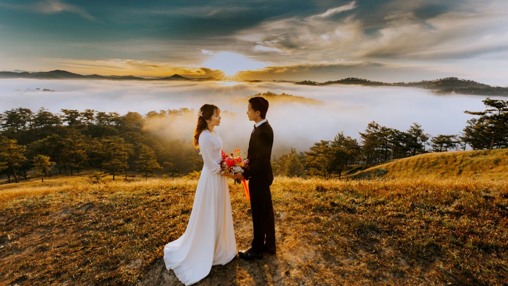 Photo by Trung Nguyen A bride and groom embrace amidst a sea of clouds at sunset in ΔΓ LαΊ‘t, creating a romantic scene.