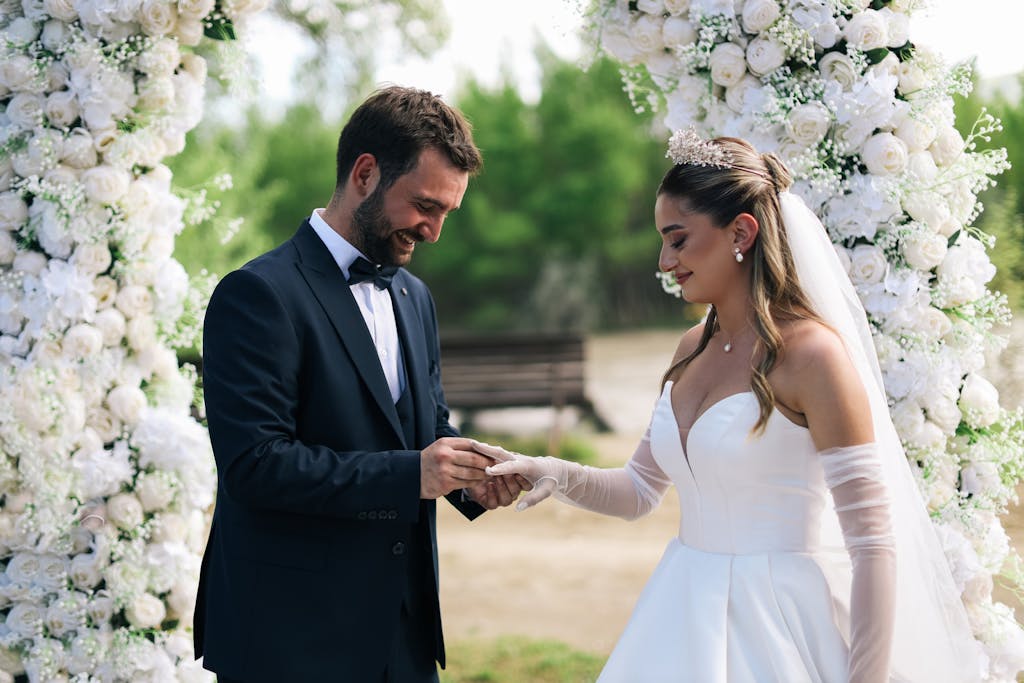 Photo by Photography Maghradze PH Bride and groom exchanging rings in a beautiful outdoor ceremony surrounded by flowers.